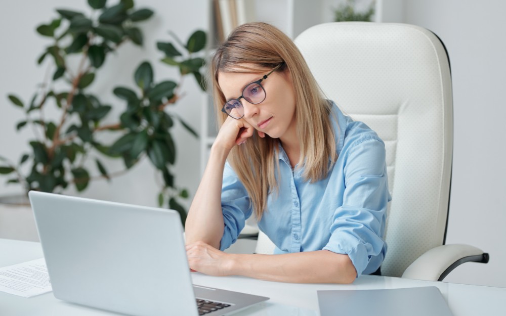 Sad woman starting at the computer because of workplace bullying